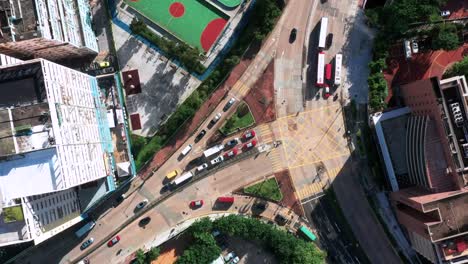 Luftbild-Aus-Der-Vogelperspektive-Mit-Blick-Auf-Die-Hochhäuser-Der-Stadt-Kowloon,-Den-Fußballplatz-Und-Den-Autobahnverkehr-In-Hongkong