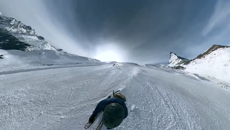 Hombre-Esquiando-Rápidamente-Por-La-Pista-Pasando-A-Otras-Personas-Mientras-La-Cámara-Se-Desplaza-Frente-A-él-Con-Una-Vista-Del-Matterhorn