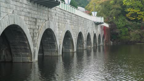 Puente-Panorámico-Sobre-El-Lago-Gwacheon-En-El-Gran-Parque-De-Seúl-En-La-Ciudad-De-Gwacheon,-Gyeonggi-do,-Corea-Del-Sur---Otoño-En-Seúl---Vista-Lateral