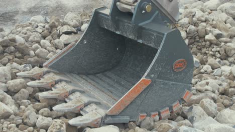 Brand-new-steel-bucket-stationary-after-first-use-on-rocks-in-quarry