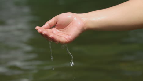 Female-Scooping-Water-From-A-River-Using-One-Hand