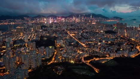 Overlooking-illuminated-Kowloon-night-cityscape-skyscrapers-fast-busy-city-life-aerial-orbit-right-hyperlapse