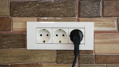 A-man's-hand-connecting-and-disconnecting-the-kitchen-appliance-to-a-triple-power-wall-socket