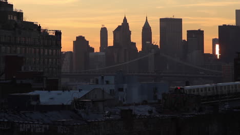 Sunrise-Subway-Train-Moves-Into-Brooklyn-From-the-City,-Across-the-Bridge,-Skyline-Buildings