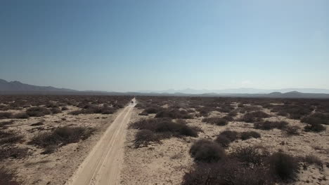 Flying-drone-footage-following-moving-car-on-a-dirt-road-highway-in-Cabo-San-Lucas