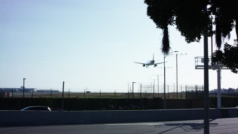 Un-Avión-Se-Acerca-A-La-Pista-Del-Aeropuerto-Laxo-Al-Otro-Lado-De-La-Calle-De-Una-Autopista-Con-Poco-Tráfico