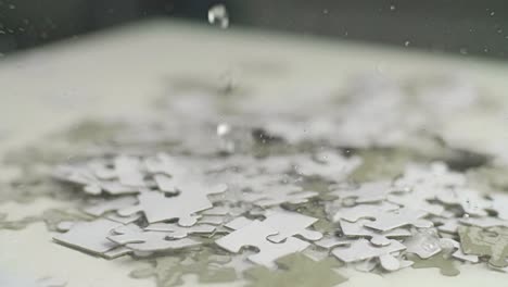 Water-drops-falling-on-white-and-gray-puzzle-pieces-laying-randomly-on-a-white-surface