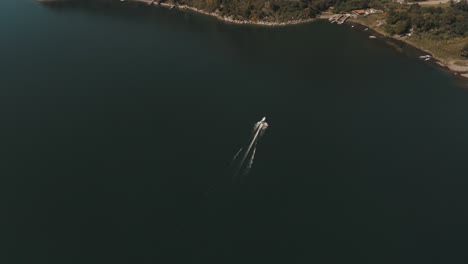 Drone-aerial-top-view-of-a-boat-driving-through-lake-Atitlan,-Guatemala