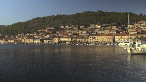 Panning-view-of-the-boats-docked-along-the-shores-of-Vela-Luka-in-Croatia-and-hills-in-the-background