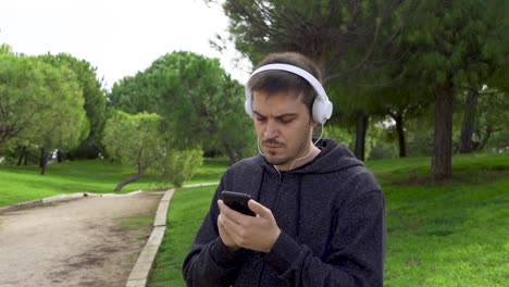Man-puts-on-headphones,-uses-the-phone-and-starts-running