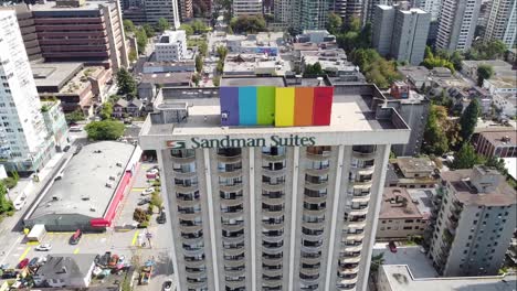 Aerial-panout-fly-over-Vancouvers-davie-street-roadside-tropical-Sandman-Hotel-swimming-pool-on-a-sunny-summer-day-with-the-Gay-pride-from-the-very-top-floor-other-high-rises-surrounding-the-inn-2-2