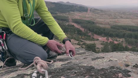 Rock-climber-securing-a-rope-on-a-carabiner-on-a-rock