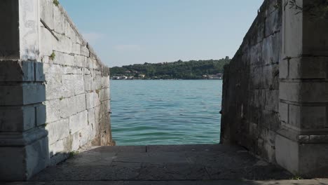 Into-the-water-in-slow-motion,-stone-brick-walls,-on-the-path-to-Lake-Garda