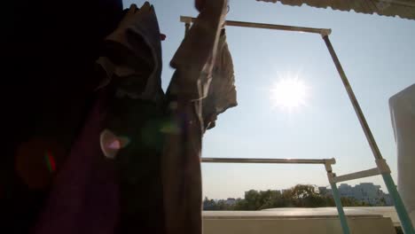 As-the-sun-shines-on-an-urban-high-rise-apartment-balcony,-a-person-hangs-laundry-to-dry