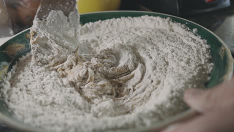 Mixing-Flour-And-Cookie-Dough-Mixture-With-A-Wooden-Spoon-In-The-Kitchen---close-up