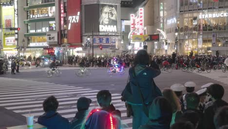 Menschenmassen-Füllen-Die-Straßenränder-Und-Beobachten-Einen-Knifflig-Geführten-Radfahrer,-Der-In-Der-Halloween-Nacht-In-Tokio,-Japan,-An-Der-Shibuya-Kreuzung-Vorbeifährt---Hyperlapse