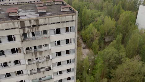 Eerie-Abandoned-Building-At-Chernobyl-Nuclear-Power-Plant-Zone-With-Autumnal-Trees-Below-In-Pripyat,-Ukraine