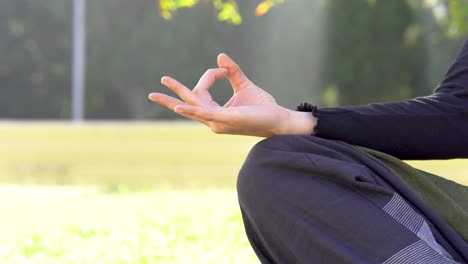 Woman-puts-hand-on-knee-in-lotus-position-practicing-yoga