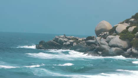 waves-crashing-against-a-stack-of-rocks-in-slow-motion,-shot-in-Tayrona-park,-Colombia