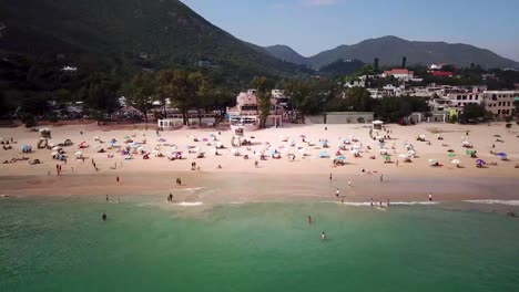 A-parallel-moving-aerial-view-of-visitors-at-Shek-O-beach-in-Hong-Kong-as-public-beaches-reopening,-after-months-of-closure-amid-coronavirus-outbreak,-to-the-public
