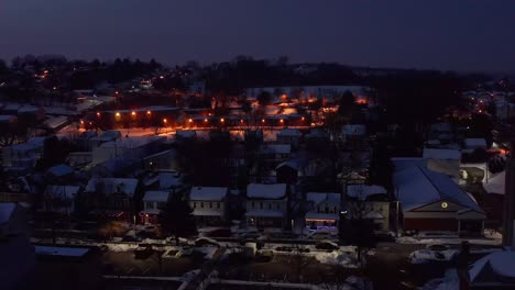 Aerial-truck-shot-of-traditional-homes-covered-in-winter-snow-at-night