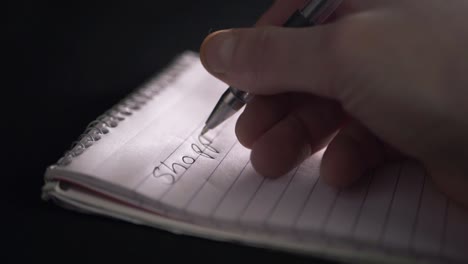 Hand-writing-shopping-list-on-notepad-close-up-shot