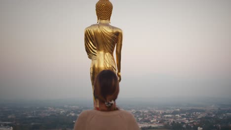 Woman-walks-close-to-golden-buddha-statue