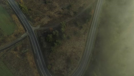 Misty-landscape-with-curved-road-in-rural-area,-Poland,-aerial