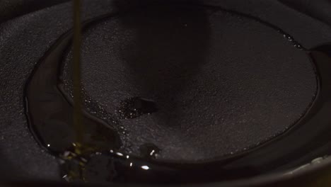 Cooking-oil-falling-on-bottom-of-black-frying-pan