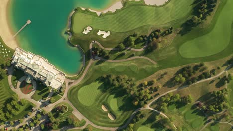 Aerial-overhead-view-of-a-golf-resort-with-beautiful-abstract-patterns,-sand-traps,-trees-tennis-courts,-and-a-turquoise-lake