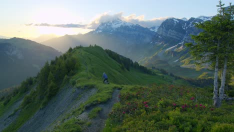 Mountain-biker-rides-down-an-alpine-ridge-at-sunrise