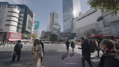 Leute,-Die-Auf-Der-Berühmten-Kreuzung-Von-Shibuya-überqueren,-Mit-Sonnenstrahl-Gegen-Gebäude-In-Tokio,-Japan