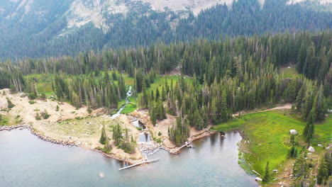 Aerial-Drone-Circling-Beaver-Damn-in-Clear-Blue-Lake-Surrounded-By-Thick-Pine-Tree-Forest-in-Nederland-Colorado-Rocky-Mountains-with-Flowing-Creek-Water