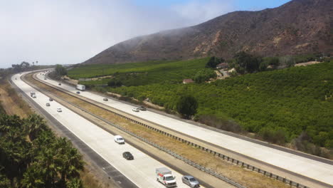 Cars-and-big-trucks-cruising-down-Freeway-101,-southern-California,-surrounded-by-amazing-landscape