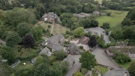 Quint-countryside-thatched-cottages-rural-Cockington-village-English-aerial-orbit-left-above-small-town