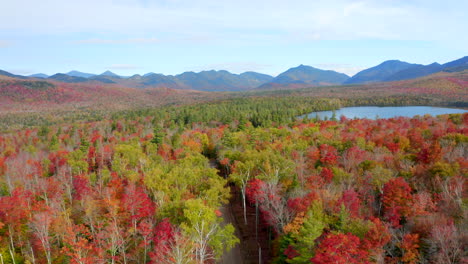 Stunning-Rising-Aerial-View-of-a-Valley-and-Mountain-Ridge-Covered-in-Vibrant-Autumn-Foliage,-Bright-Red-and-Yellow-Leaves,-Drone-Footage-of-the-Adirondacks,-New-York
