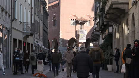 People-Wearing-Medical-Masks-For-Covid-19-Pandemic,-Walking-On-City-Street-On-A-Sunny-Day-Of-January-In-Monza,-Northern-Italy---Medium-Shot
