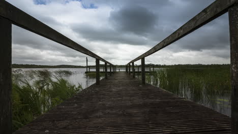 Time-lapse-of-an-old-timber-jetty-leading-to-local-lake-in-rural-landscape-of-Ireland