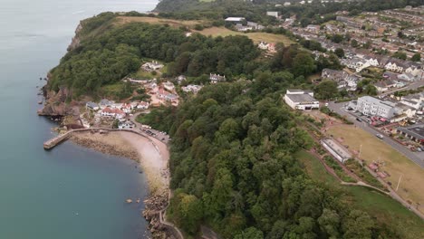 Aerial-dolly-side-shot-of-Babbacombe-Beach,-Shore,-overgrown-cliffs-and-Torquay-City-on-top-of-mountain