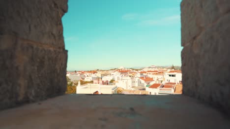 Portugal-Loule-city-through-castle-wall-battlements-under-blue-sky-with-pull-in-camera-movement-4K