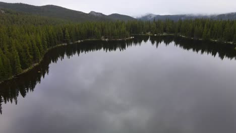 Forward-dolly-view-over-a-very-still-morning-lake-surrounded-by-woods-in-the-Bighorn-National-Forest-in-Wyoming