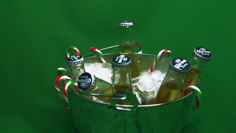 1-2-Rotierender-Eiskübel-Mit-Grünem-Bildschirm,-Gefüllt-Mit-Einem-6er-Pack-Kühler,-Erfrischender,-Durstlöschender-Corona-Extra-Coronita-Flaschenbiere-Mit-Glaskappen-Und-Festlich-Hängenden-Zuckerstangen,-Bereit-Für-Weihnachtsspaß
