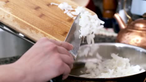 Slomo-shot-of-woman-hand-scraping-cut-onions-into-pan