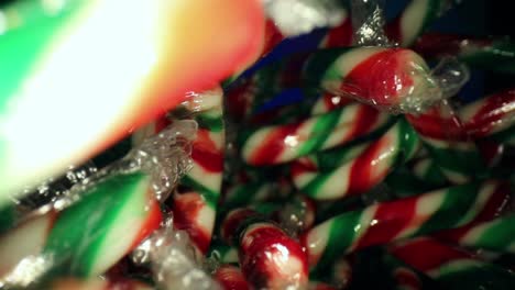 Quickly-moving-towards-a-large-pile-of-wrapped-red,-white,-green-mini-candy-canes