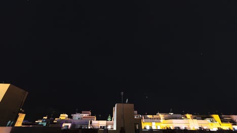 Zeitraffer-Des-Nachthimmels-Mit-Vielen-Sternen-Und-Satelliten-Mit-Gebäuden-Im-Hintergrund
