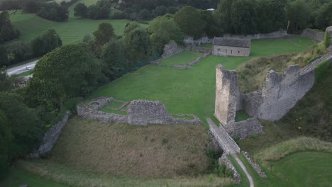 Drone-shot-alongside-Pickering-Castle,-showing-the-Motte-and-Bailey,-ruined-towers-and-walls-and-the-old-Chapel