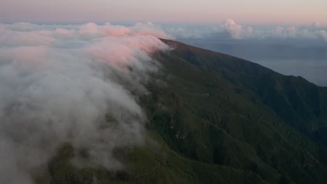 Clouds-forming-above-mountains-and-flowing-over-edge-in-Madeira-at-dawn