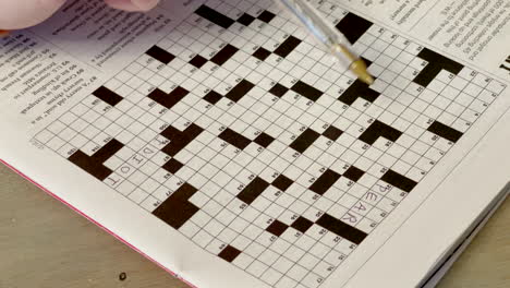 Closeup-of-a-woman-doing-a-crossword-puzzle-with-a-pen