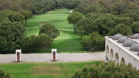 Plano-General-De-Jugar-Golfistas-En-Campos-Verdes-De-Campo-De-Golf-Con-Carritos-De-Caddie-Y-árboles-Durante-El-Día