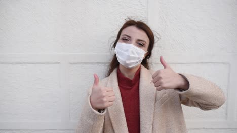 Slow-Motion:Beautiful-girl-wearing-protective-medical-mask-and-fashionable-clothes-does-thumbs-up-gesture